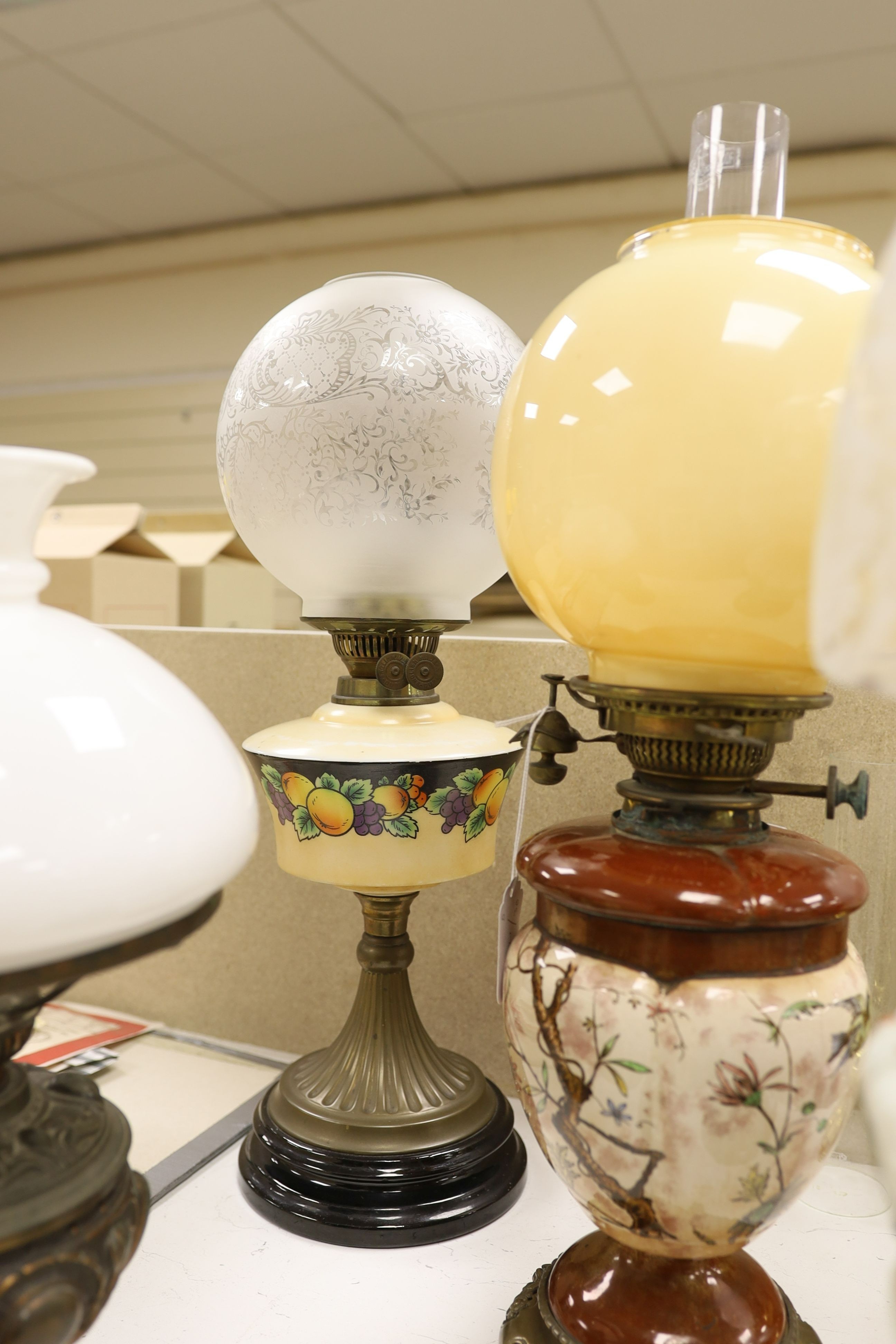 A Doulton style pottery oil lamp and four other glass and brass oil lamps, tallest 54 cms including glass shade.